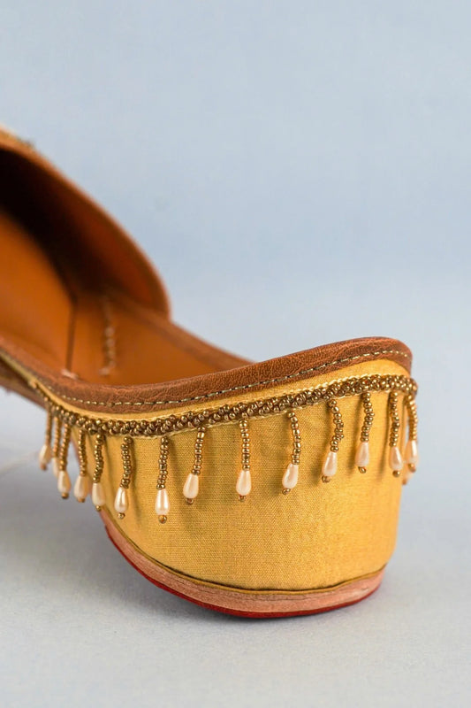 Close-up of handcrafted women's jutti heel with brown leather trim and intricate bead tassel detailing