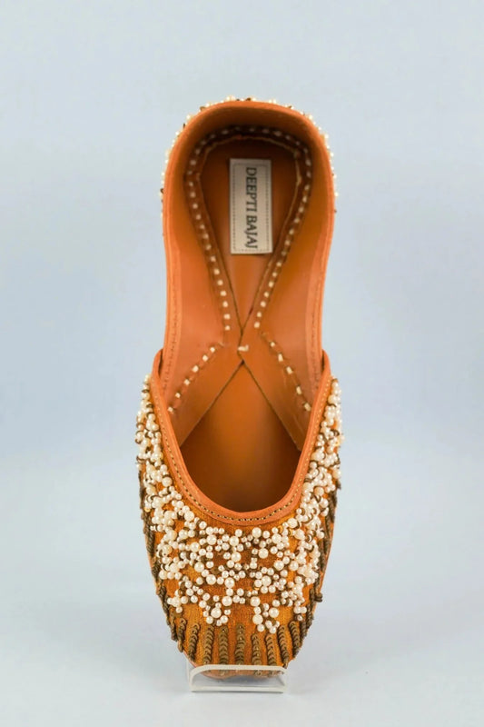 Handcrafted women's jutti by Deepti Bajaj with intricate pearl and bead embroidery on tan fabric