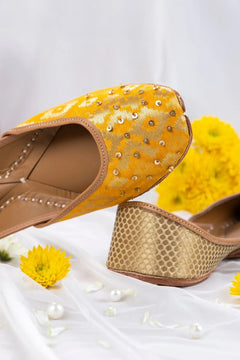 Yellow and gold handcrafted jutti for women with sequin embellishments and patterned heel on white fabric with yellow flowers